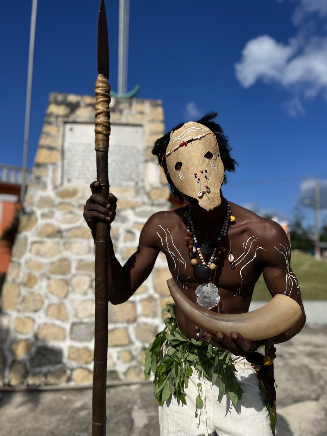 A masked figure holding a horn in Accompong